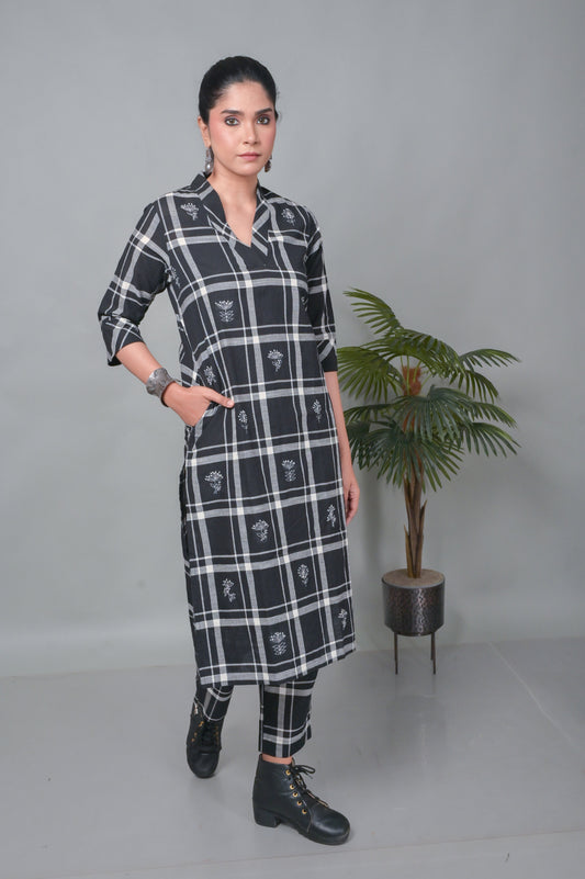 Woman wearing a black and white checkered dress with a plant in the background