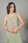 Woman wearing a light green sleeveless dress with colorful patterns on a gray background