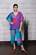 A woman modeling a purple half and half handwoven kaftan top with geometric patterns, paired with matching pants.