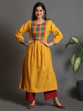 A woman posing in a yellow handwoven pleated kurta with multi-color checks on the yoke and mirror work on the chest.
