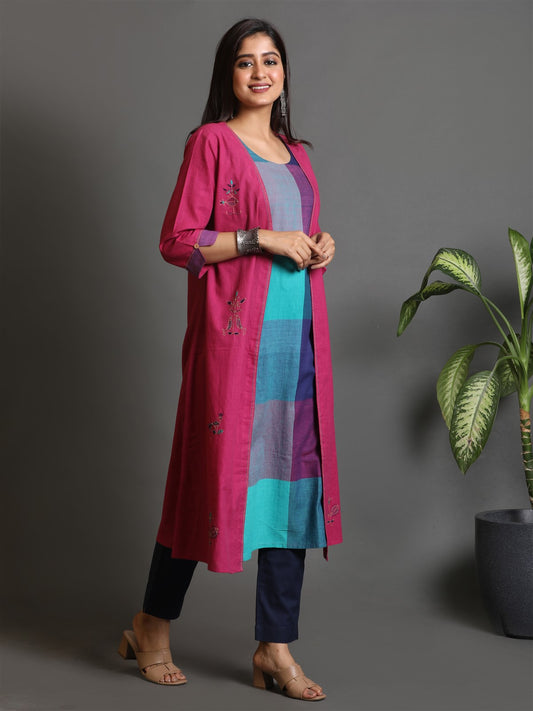 A woman modeling a fuchsia handwoven kurta with jacket style all over Kantha hand embroidery detailing, paired with blue pants.