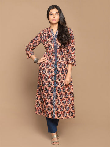 A woman standing and posing in a maroon and beige floral printed cotton A-line pleated kurta with Kantha hand embroidery detailing.