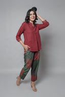 Woman wearing a red shirt and patterned pants against a red background