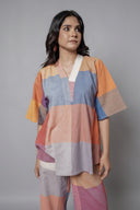 Woman wearing a colorful, patchwork-style outfit against a red background